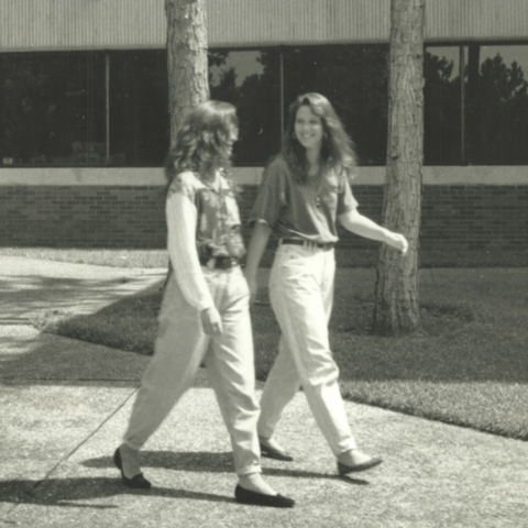 Two students walking on campus. Vintage photo from the 1980s